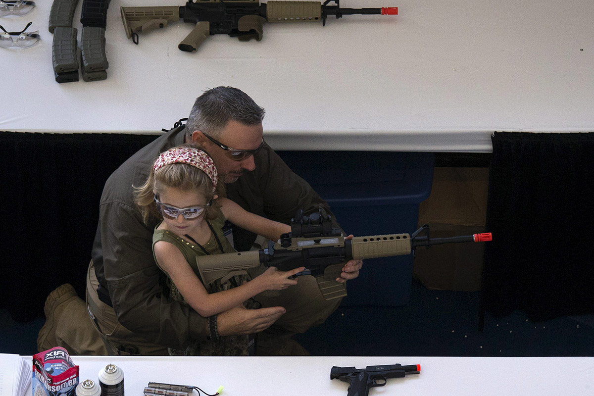 Un hombre enseña a su hija a manejar el arma en el 'Día de la Juventud' de la NRA.